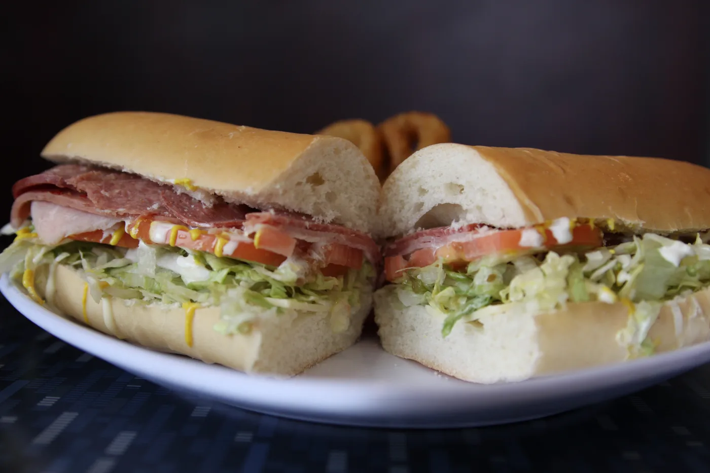 A foot long Combo Sub cut in half, with meats, tomato and lettuce